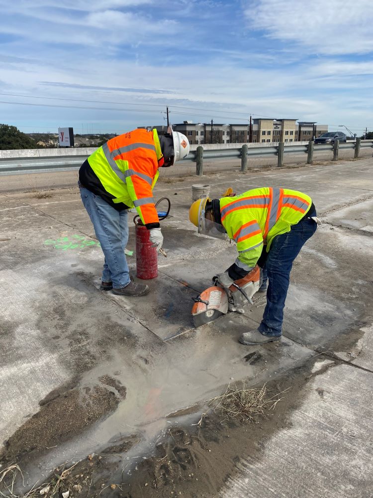 Oak Hill Parkway team members use saws to cut concrete next to the US 290 bridge over Old Fredericksburg Road. Several existing bridges will be widened along US 290 east of MoPac as part of the Oak Hill Parkway Project. January 2022