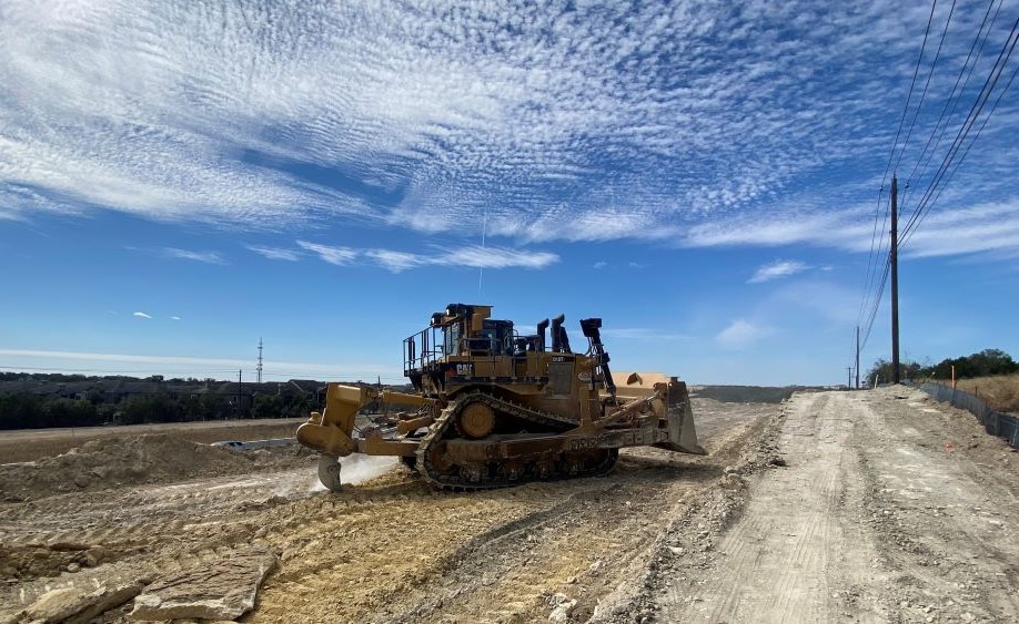 This loader crushes rock with a dragging hook along the future US 290 frontage road near RM 1826. The hook is used to remove soft rock before crews begin using excavation machines. March 2022