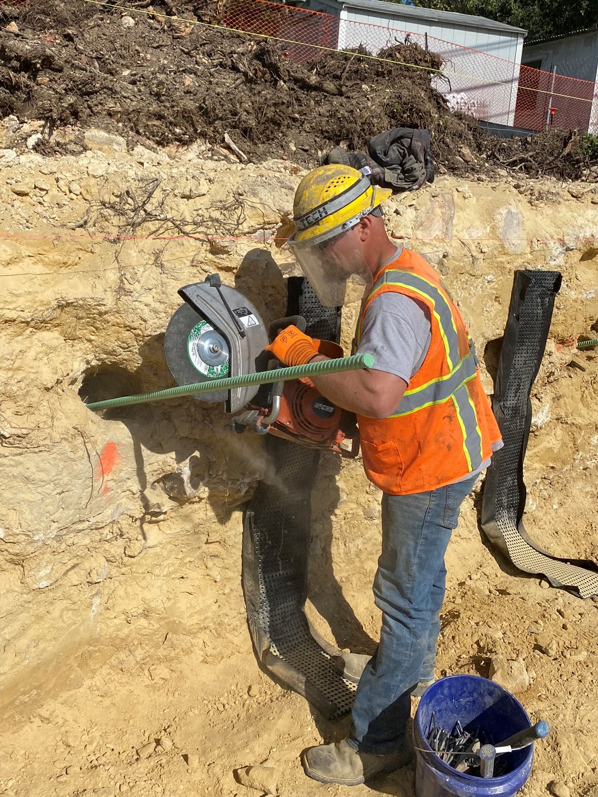 An Oak Hill Parkway team member uses a grinder blade to cut a soil nail steel anchor bolt to the proper length during retaining wall construction on US 290 near Circle Drive. December 2021 