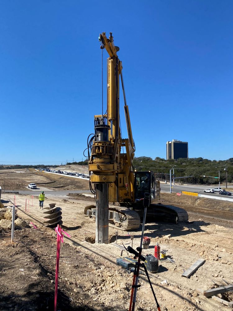 This drill bores a hole into the rock near US 290 and Convict Hill Road to hold a reinforced concrete column foundation for a future sound wall. The team is building sound walls first to help reduce both construction noise as well as future traffic noise.
