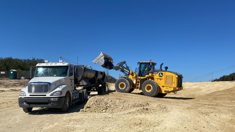 A loader fills a hauling truck with recently excavated rock and dirt near US 290 and El Rey Boulevard. While most excavation activities take place during the day, loading and hauling activity occurs around the clock to reduce the project schedule while al