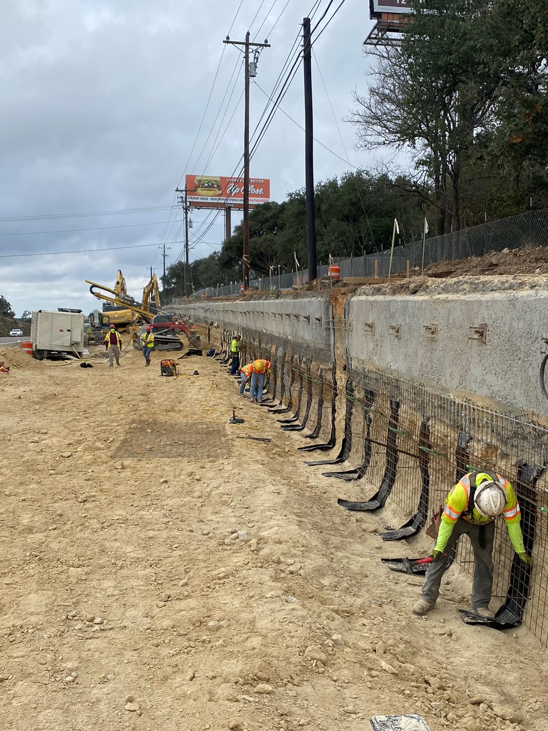 Oak Hill Parkway workers install the wire mesh reinforcement for the second five-foot layer of a retaining wall. The first five feet on top is complete. December 2021