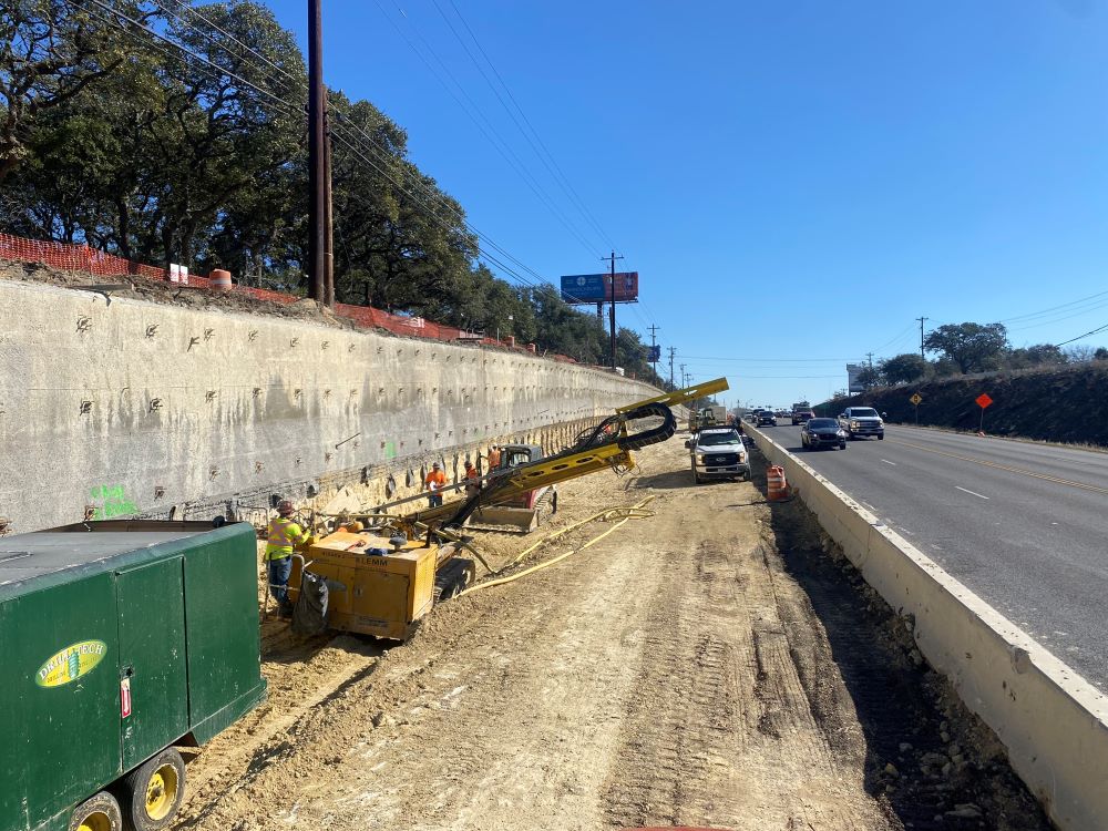 Large steel anchor nails are installed with this horizontal drill rig for a new retaining wall near US 290 and Circle Drive. This type of soil nail wall construction allows for a permanent wall to be built while excavating in narrow areas, such as here al