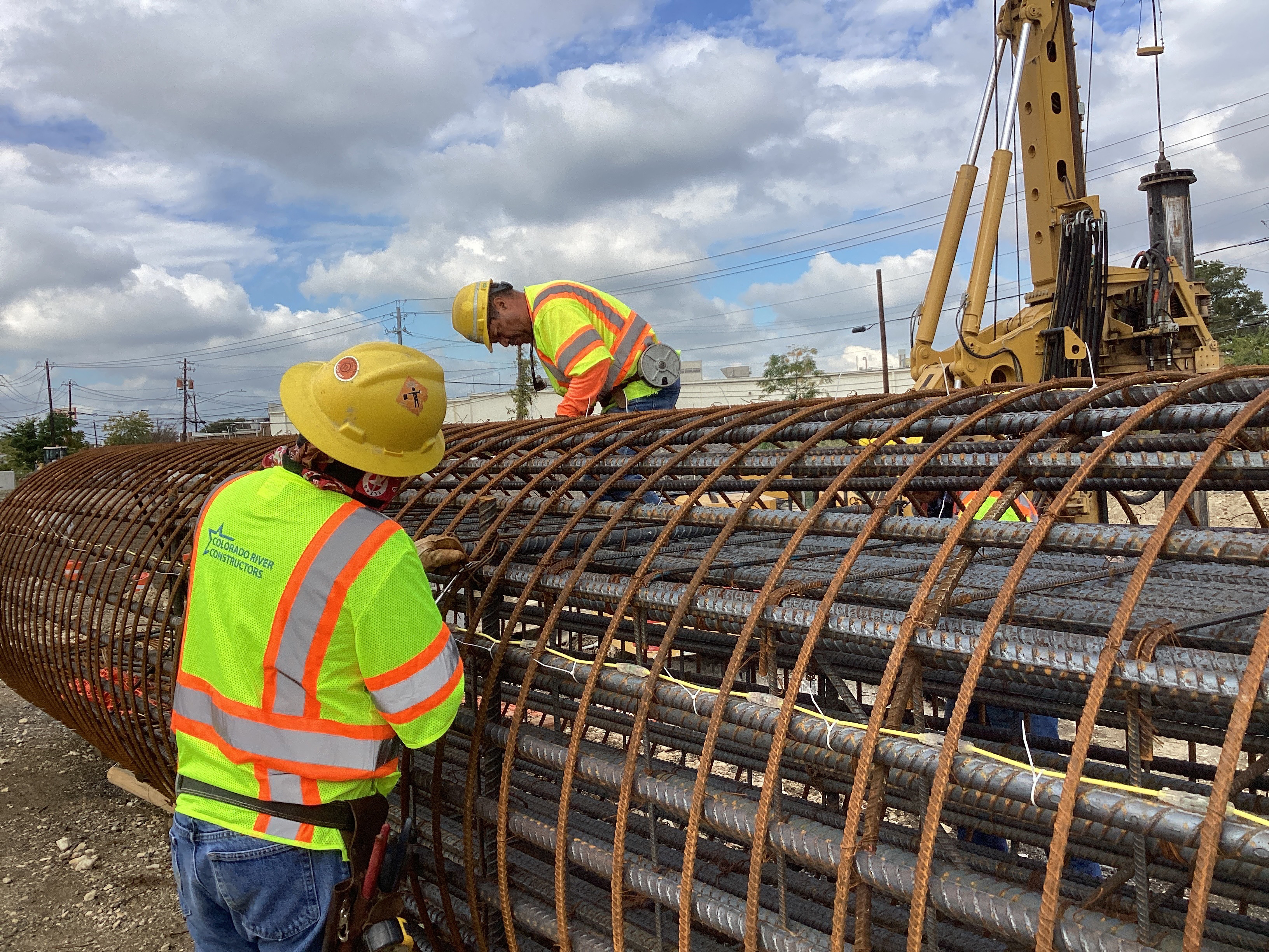 Workers construct bridge drilled shaft reinforcement cages.